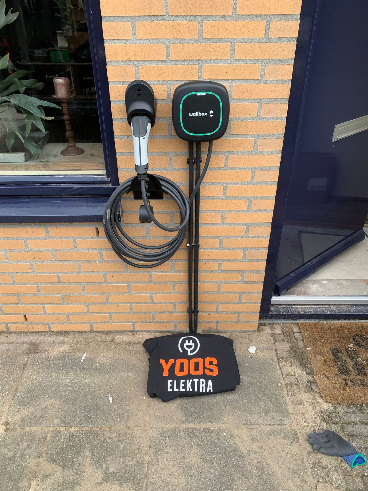 Wallbox laadpaal met kabel aan de gevel van een woning, geïnstalleerd door Yoos Elektra